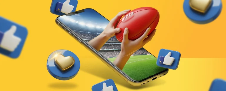 A 3D illustration of two hands holding a red AFL football emerging from a smartphone screen set in a stadium, with floating social media thumbs up and heart icons on a bright yellow background.